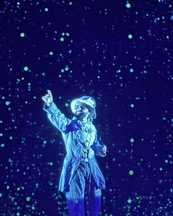 Actor pointing toward the roof all in shades of blue with stars