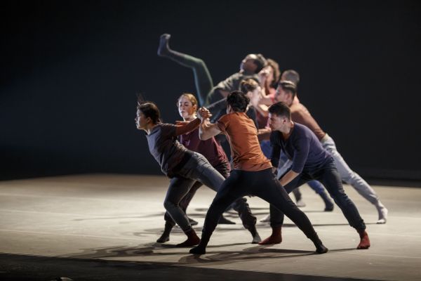 Multiple dancers on stage leaning forward.