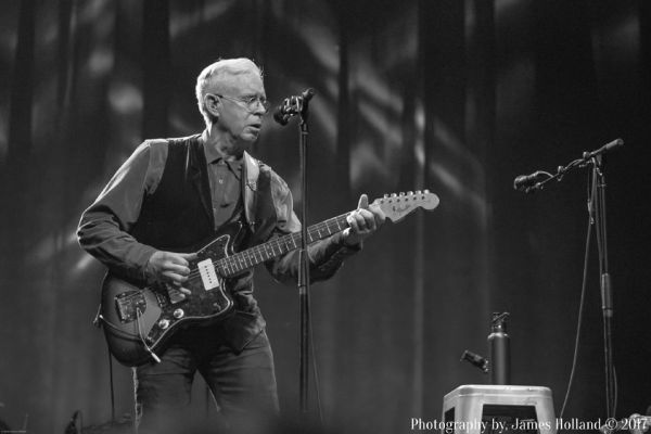 Bruce Cockburn in black and white playing electric guitar.