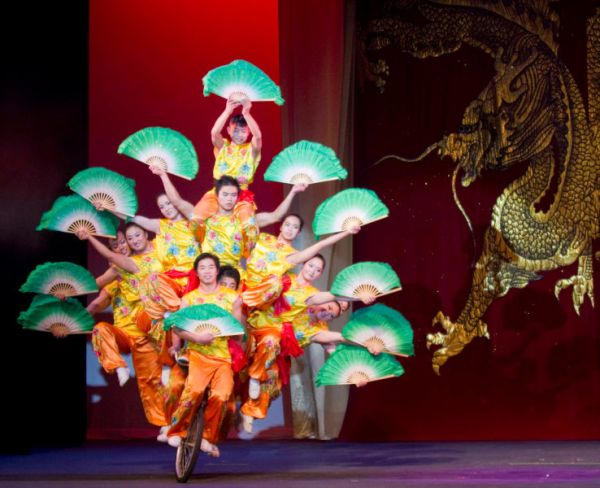 many performers on one unicycle with colourful fans