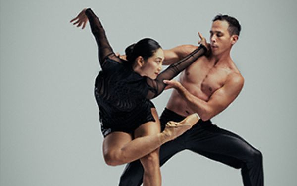 two ballet dancers in black, in front of a white screen