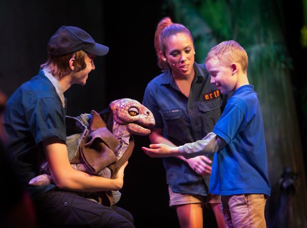 Erth's Dinosaur Zoo Live - photo credit C Waits child petting a baby dinosaur on stage