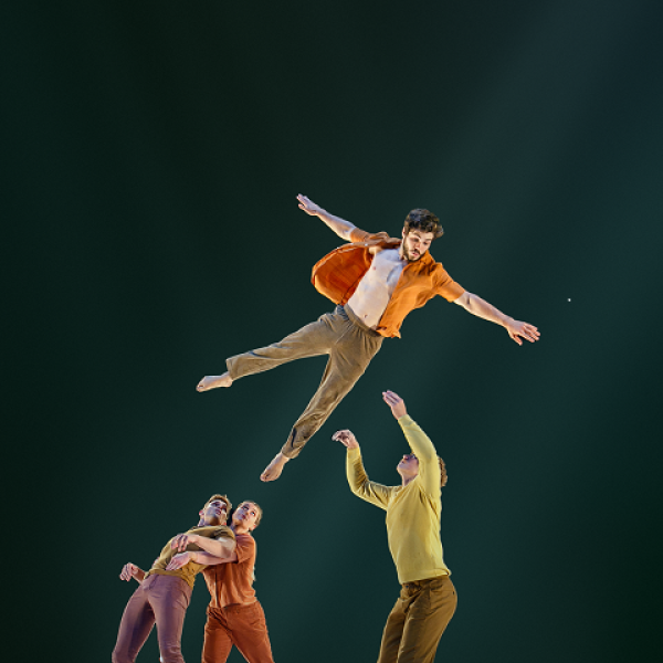 Performers onstage tossing one of the men into the air.