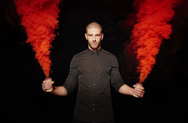 Darcy Oake with two red dye bombs going off in each hand
