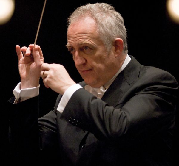 conductor with his hands in front of his face