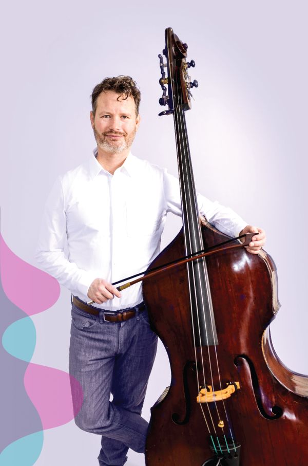 Bass player in a white shirt, standing beside his bass