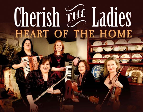 Five women in a kitchen holding musical instruments