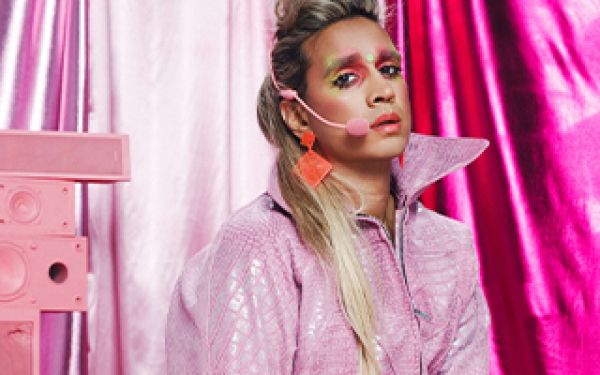 performer all in pink, with a body mic and sad expression on their face