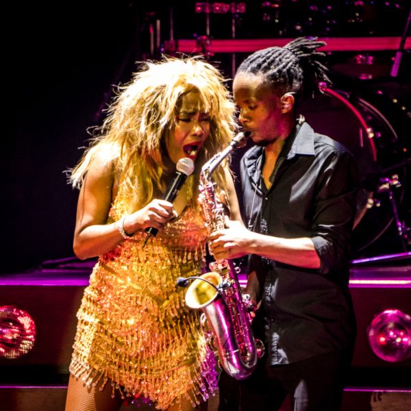 female performer in gold dress with saxophone player in black