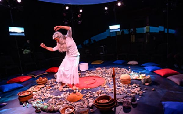performer in white dancing in a round circle of stone on the ground