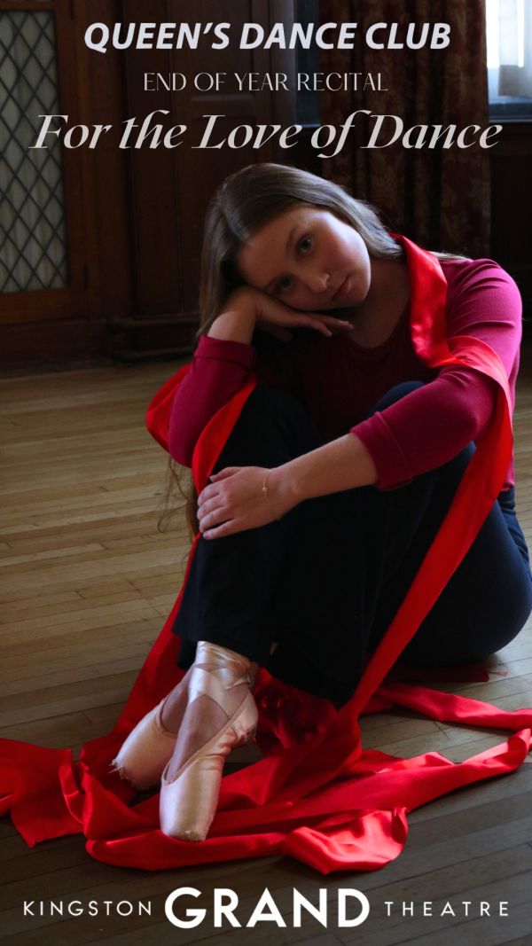 dancer seated on stage, dressed in red with pink ballet shoes