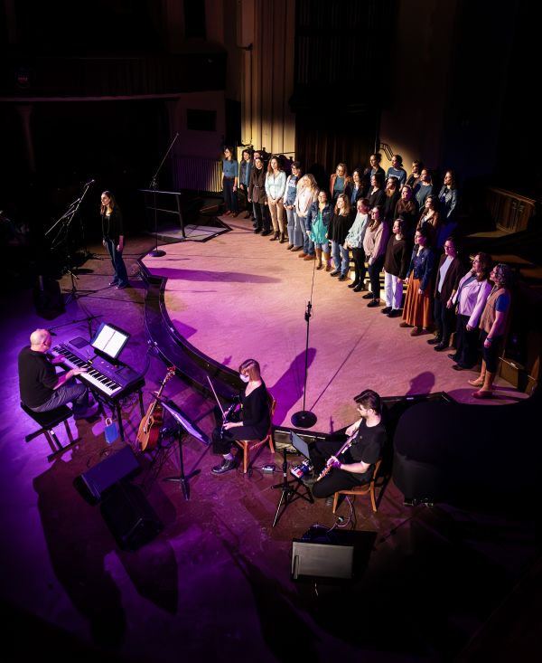 a stage showing singers on the right side with a player seated at a piano on the right