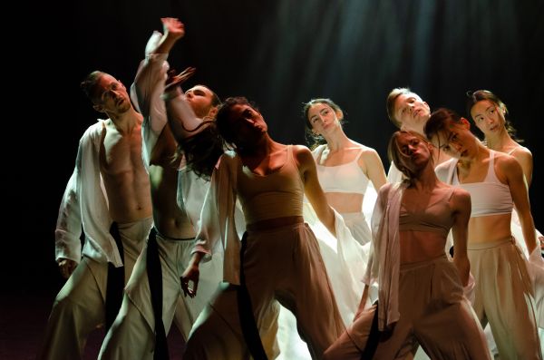 multiple dancers on stage, some with their arms in the air