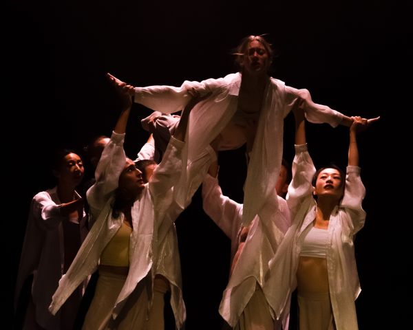 multiple dancers on stage, some with their arms in the air