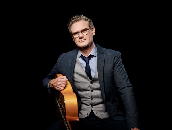 Jesse Cook, leaning against his guitar