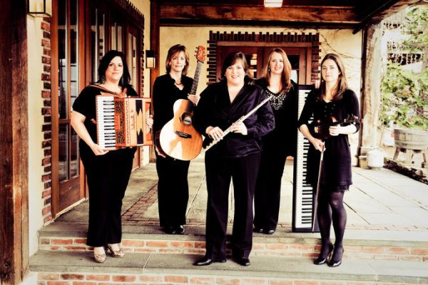 Five women musicians standing outside holding their instruments